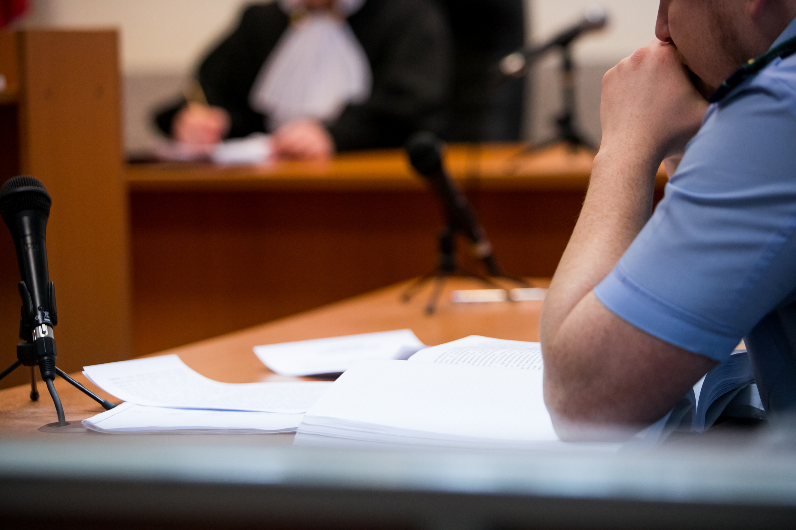 A man in court thinking with a judge in the background